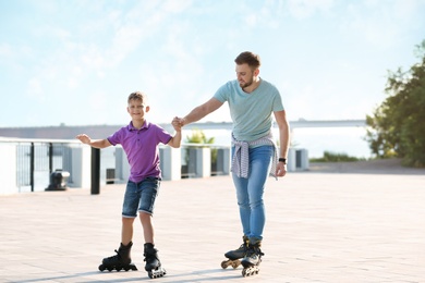 Father and son roller skating on city street