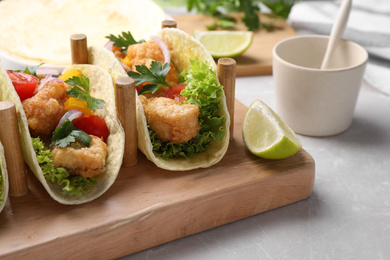 Photo of Yummy fish tacos served on marble table, closeup