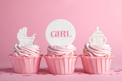 Beautifully decorated baby shower cupcakes for girl with cream and toppers on pink background