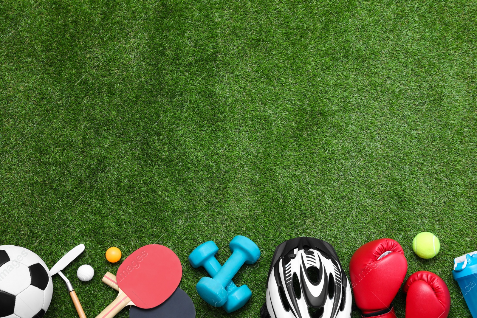 Photo of Different sport equipment on green grass, flat lay. Space for text