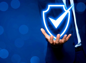 Image of Anti-fraud security system. Man with illustration of checkmark in shield on blue background, closeup. Space for text