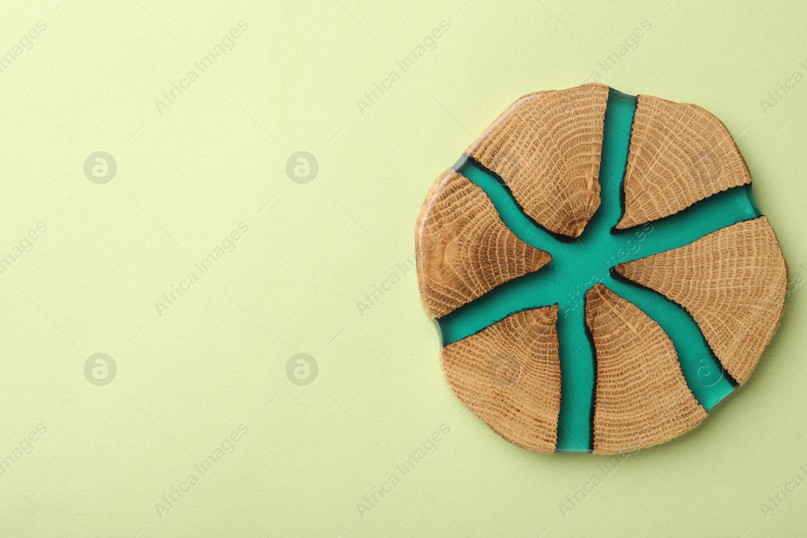 Photo of Stylish wooden cup coaster on pale green background, top view. Space for text