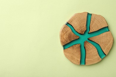 Photo of Stylish wooden cup coaster on pale green background, top view. Space for text