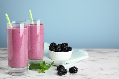 Delicious blackberry smoothie in glasses on marble table. Space for text