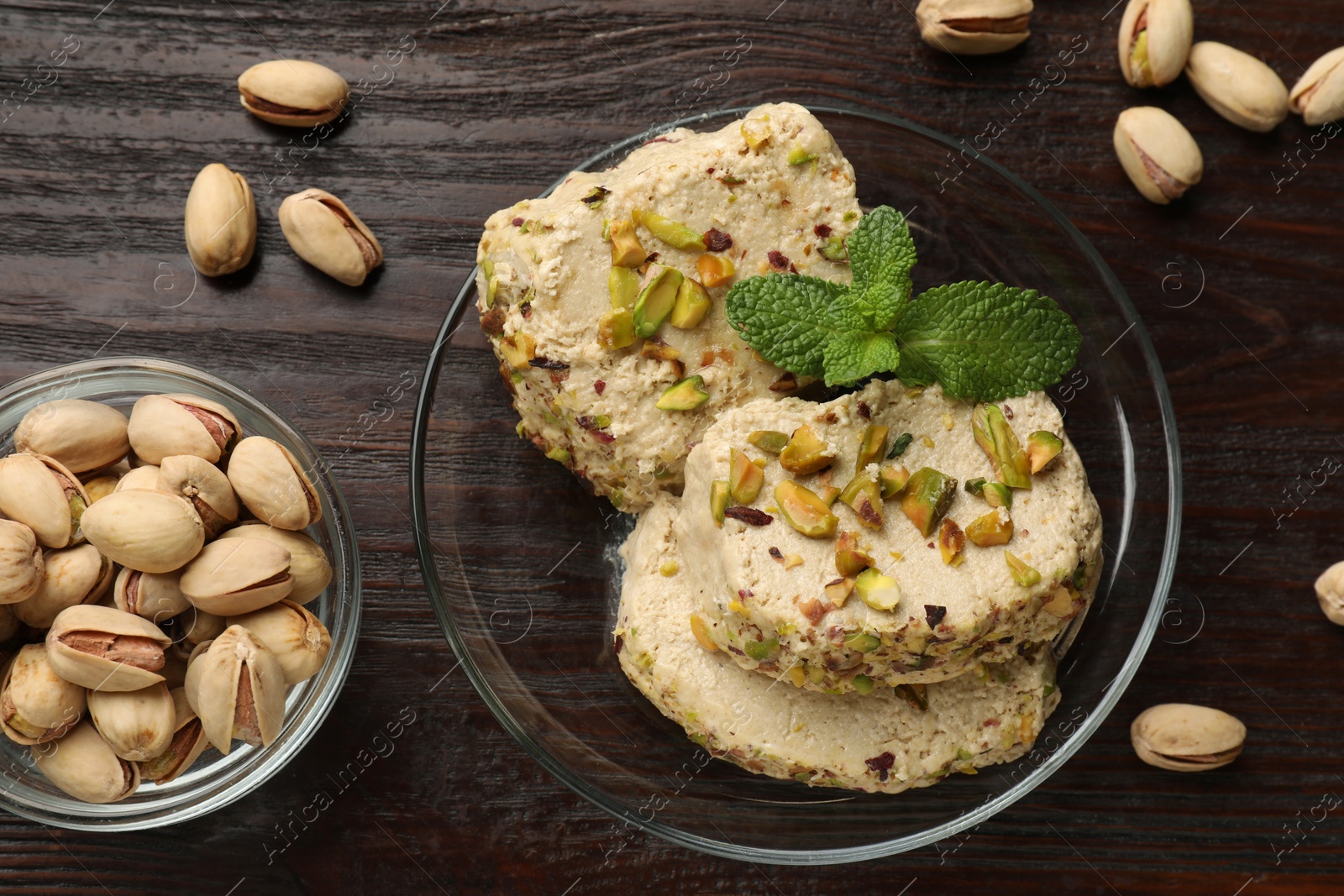 Photo of Tasty halva with pistachios and mint on wooden table, flat lay