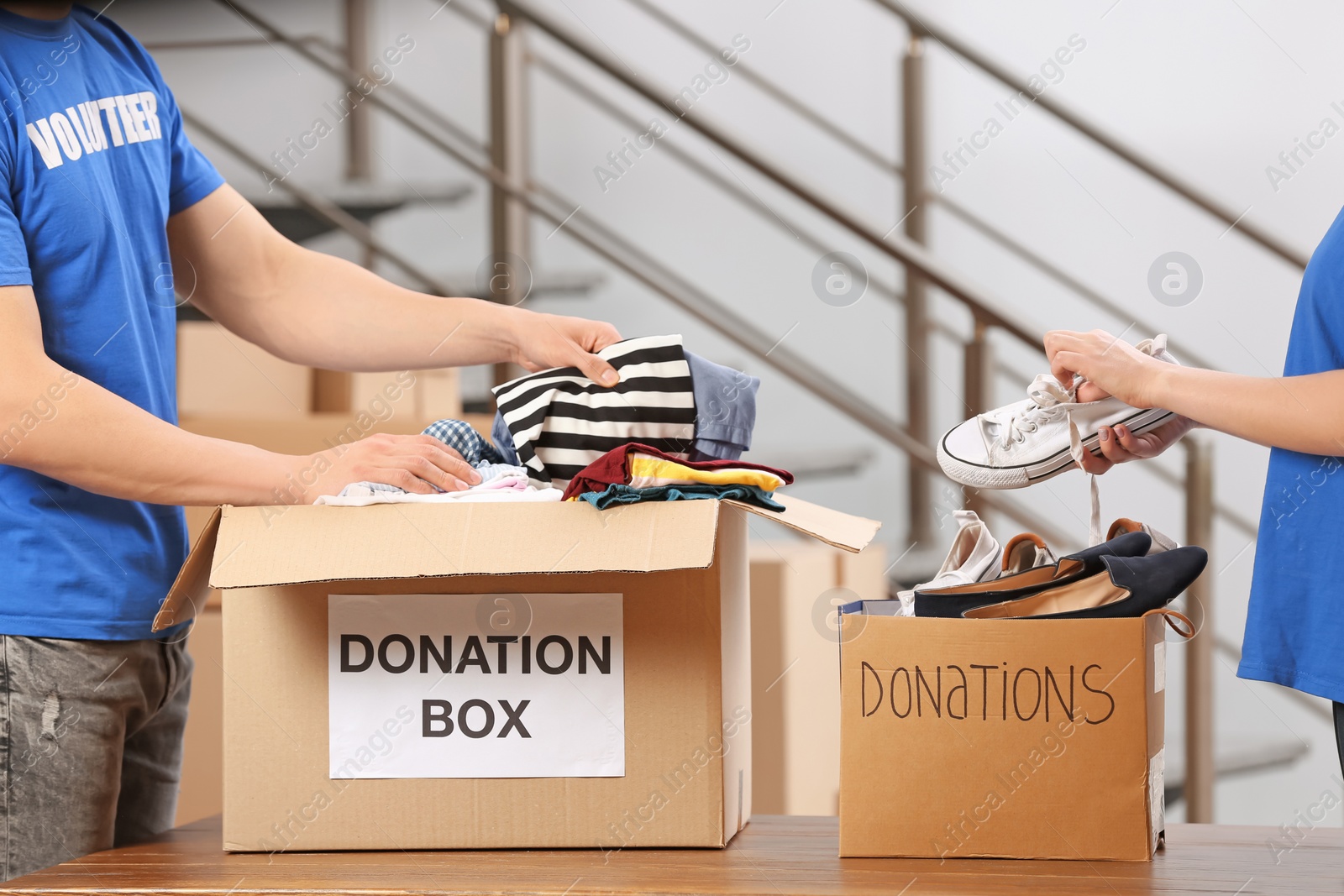 Photo of Volunteers putting clothes and shoes in donation boxes indoors