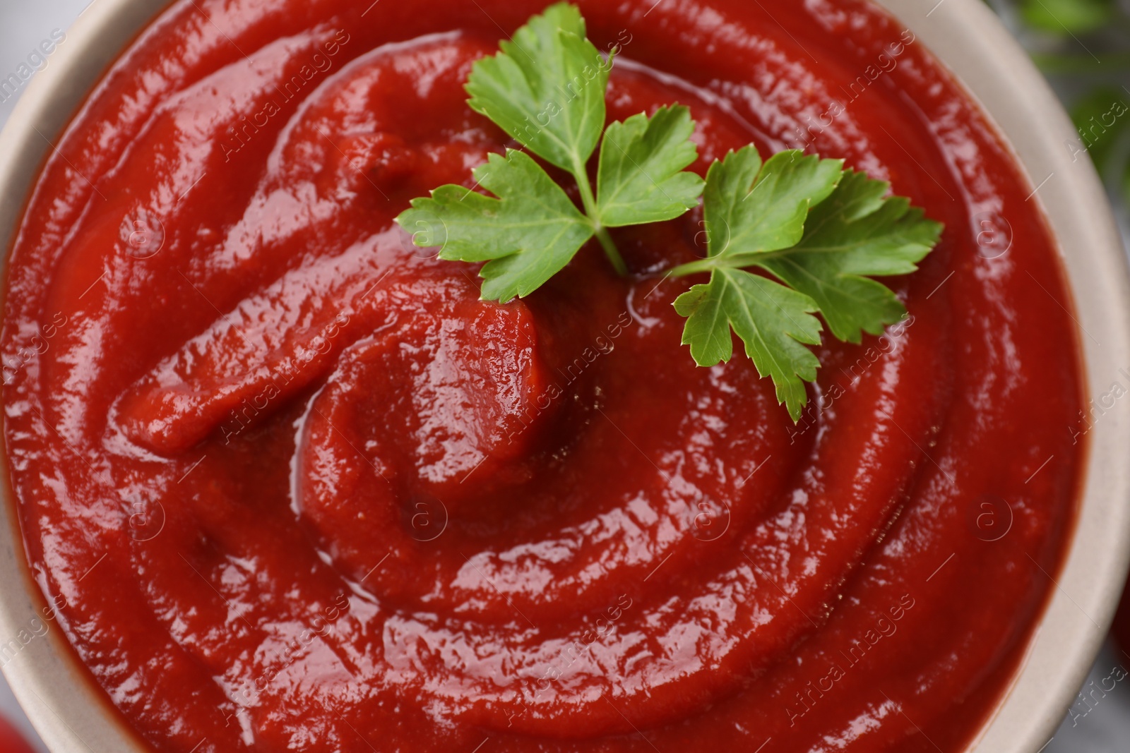 Photo of Organic ketchup and parsley in bowl, top view. Tomato sauce