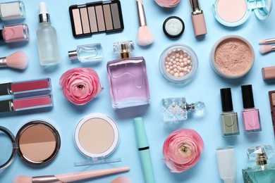 Flat lay composition with different makeup products and beautiful spring flowers on light blue background