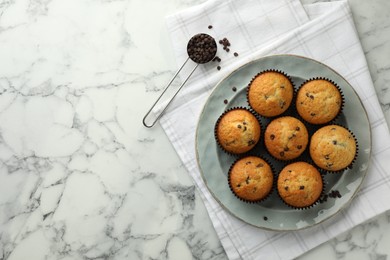 Photo of Delicious sweet muffins with chocolate chips on white marble table, top view. Space for text