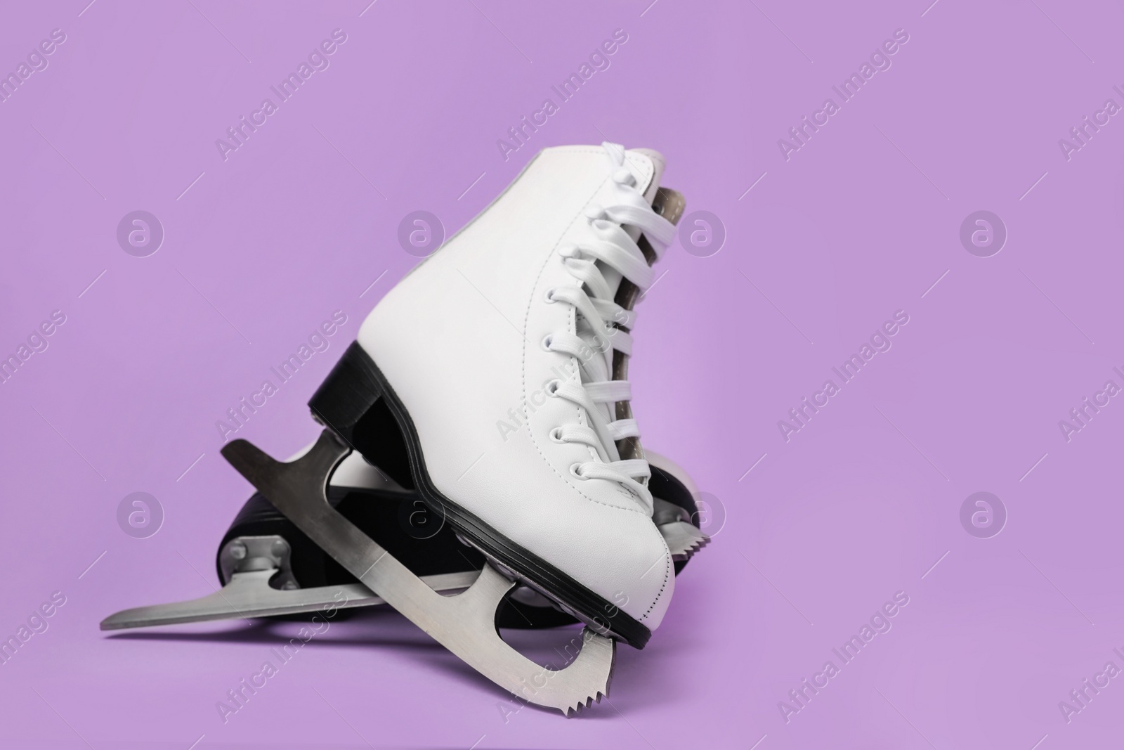 Photo of Pair of figure ice skates on violet background