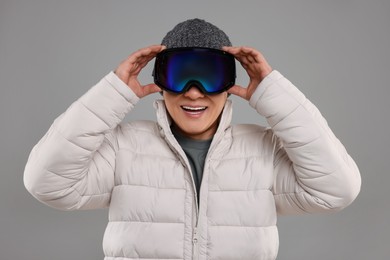 Winter sports. Happy man in ski goggles on grey background