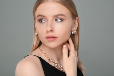 Photo of Beautiful young woman with elegant jewelry on gray background