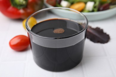 Photo of Vinegar in glass on white tiled table, closeup