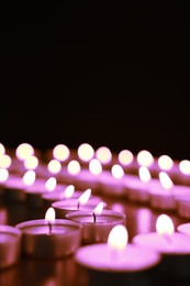 Beautiful burning violet candles on black background. Funeral attributes