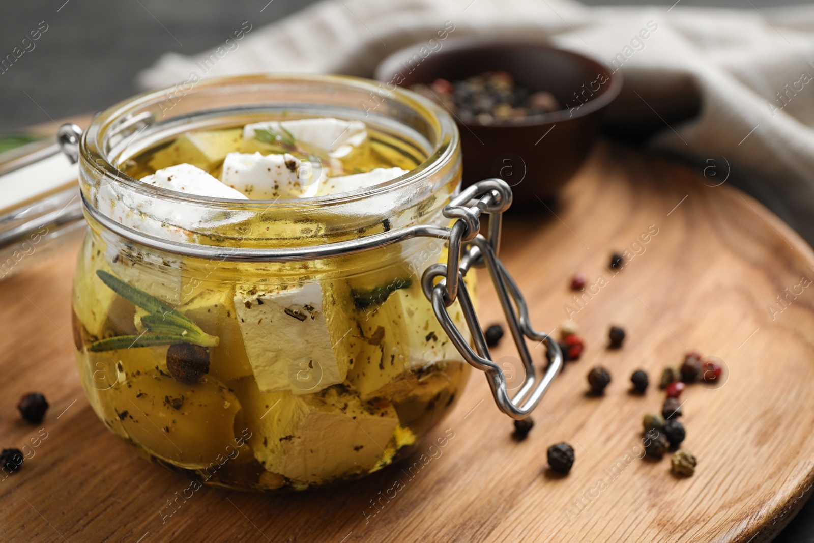 Photo of Jar with feta cheese marinated in oil on table. Pickled food