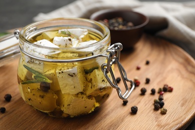 Jar with feta cheese marinated in oil on table. Pickled food