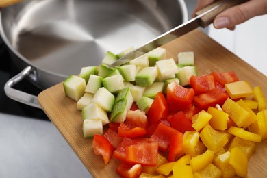 Photo of Woman putting cut vegetables into saute pan in kitchen, closeup