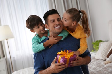 Photo of Man receiving gift for Father's Day from his children at home