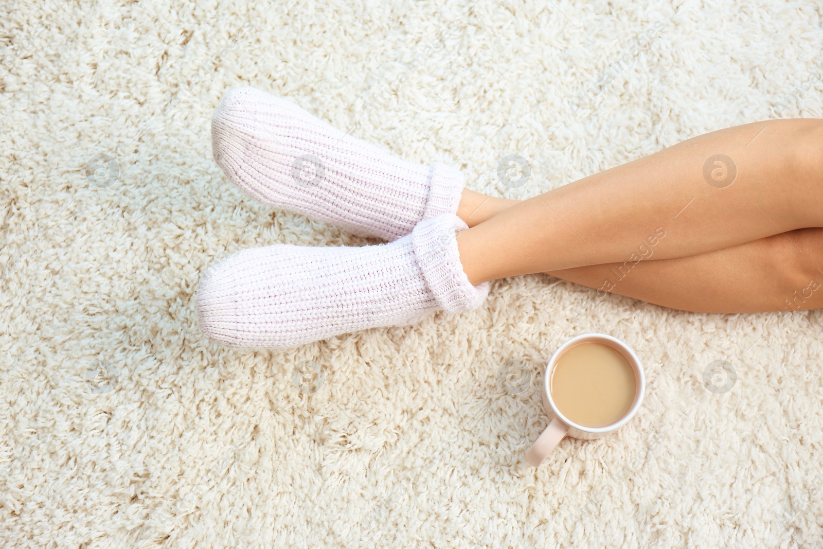 Photo of Woman and cup of coffee on carpet, closeup. Floor heating