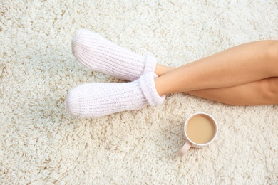 Photo of Woman and cup of coffee on carpet, closeup. Floor heating