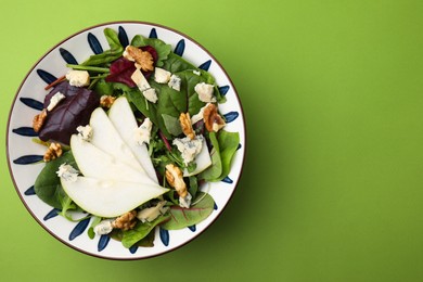 Photo of Delicious pear salad in bowl on green background, top view. Space for text