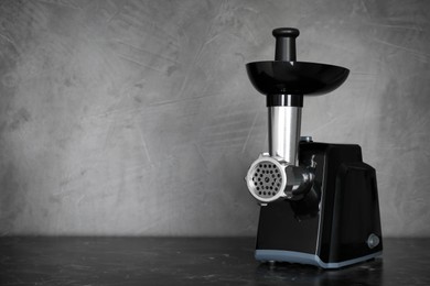Photo of Modern electric meat grinder on black table. Space for text