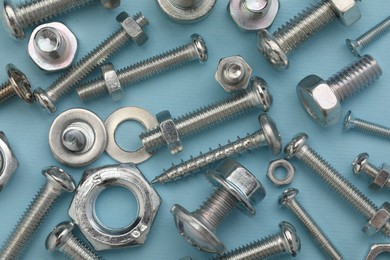 Photo of Many different fasteners on light blue background, flat lay