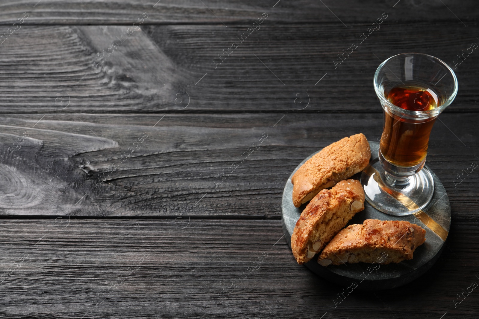 Photo of Tasty cantucci and glass of liqueur on wooden table, space for text. Traditional Italian almond biscuits