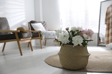 Photo of Bouquet of beautiful peony flowers in basket on floor. Space for text
