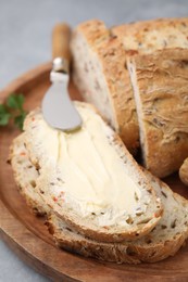 Photo of Tasty bread with butter and knife on grey table, closeup