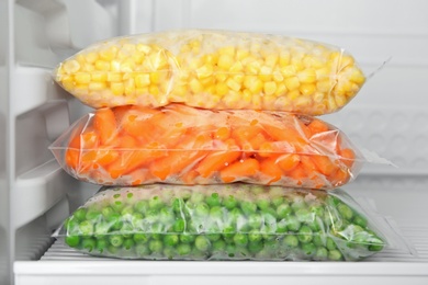 Plastic bags with deep frozen vegetables in refrigerator