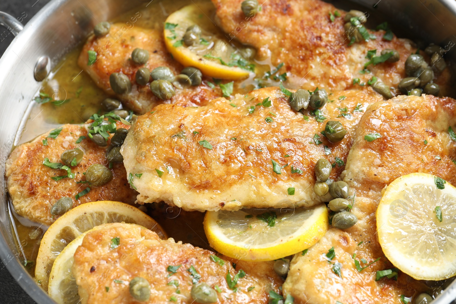 Photo of Delicious chicken piccata with herbs in pot, closeup