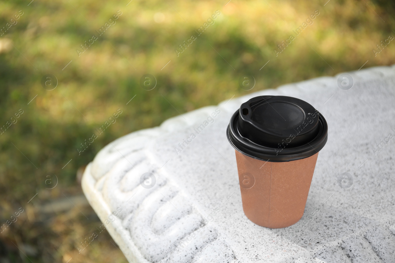 Photo of Cardboard cup with tasty coffee on stone bench outdoors. Space for text