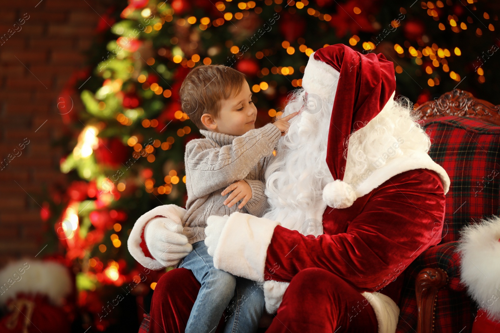 Photo of Santa Claus and little boy near Christmas tree indoors