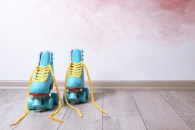 Photo of Vintage roller skates on floor near color wall. Space for text