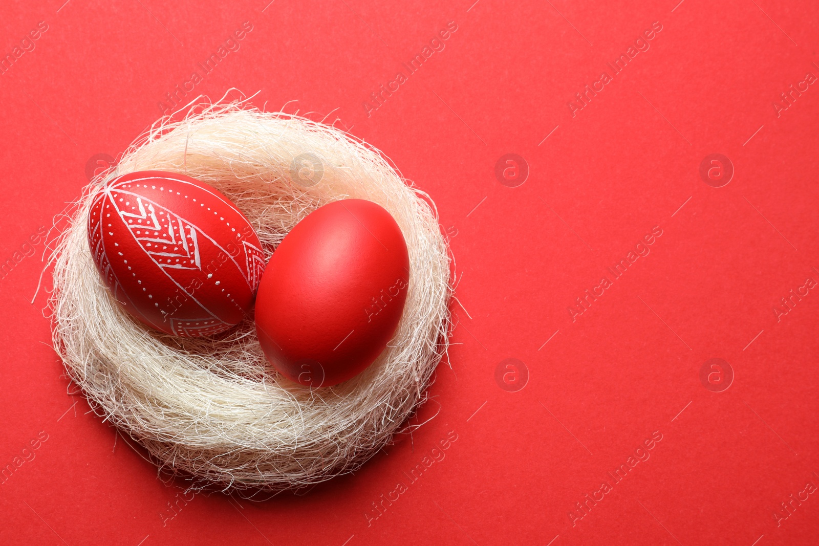 Photo of Nest with red painted Easter eggs on table, above view. Space for text