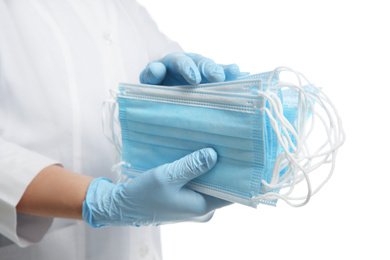 Photo of Doctor in latex gloves holding disposable face masks on white background, closeup. Protective measures during coronavirus quarantine