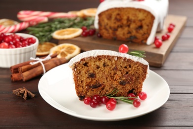 Photo of Traditional classic Christmas cake decorated with cranberries and rosemary on wooden table