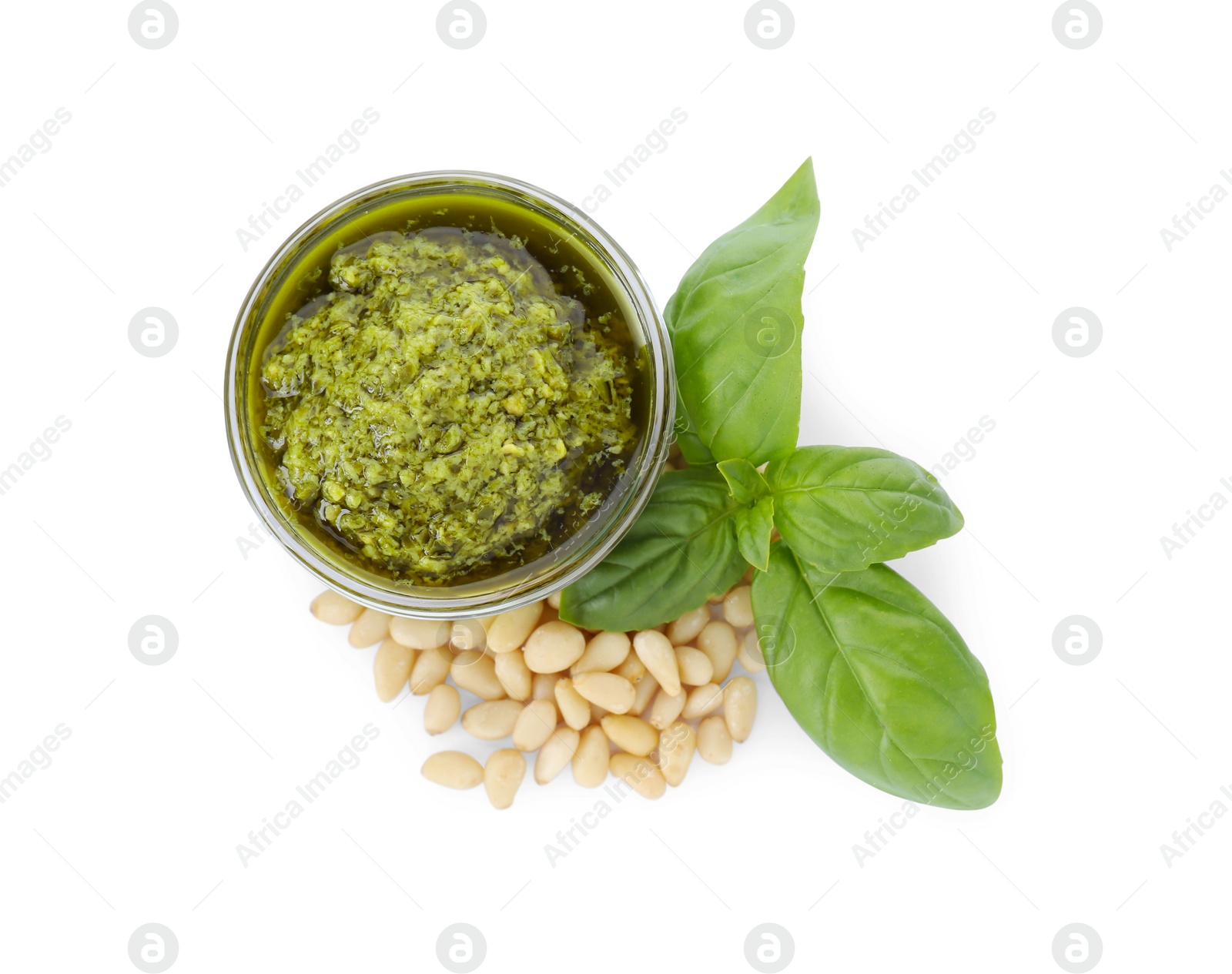 Photo of Tasty pesto sauce in glass bowl, pine nuts and basil on white background, top view