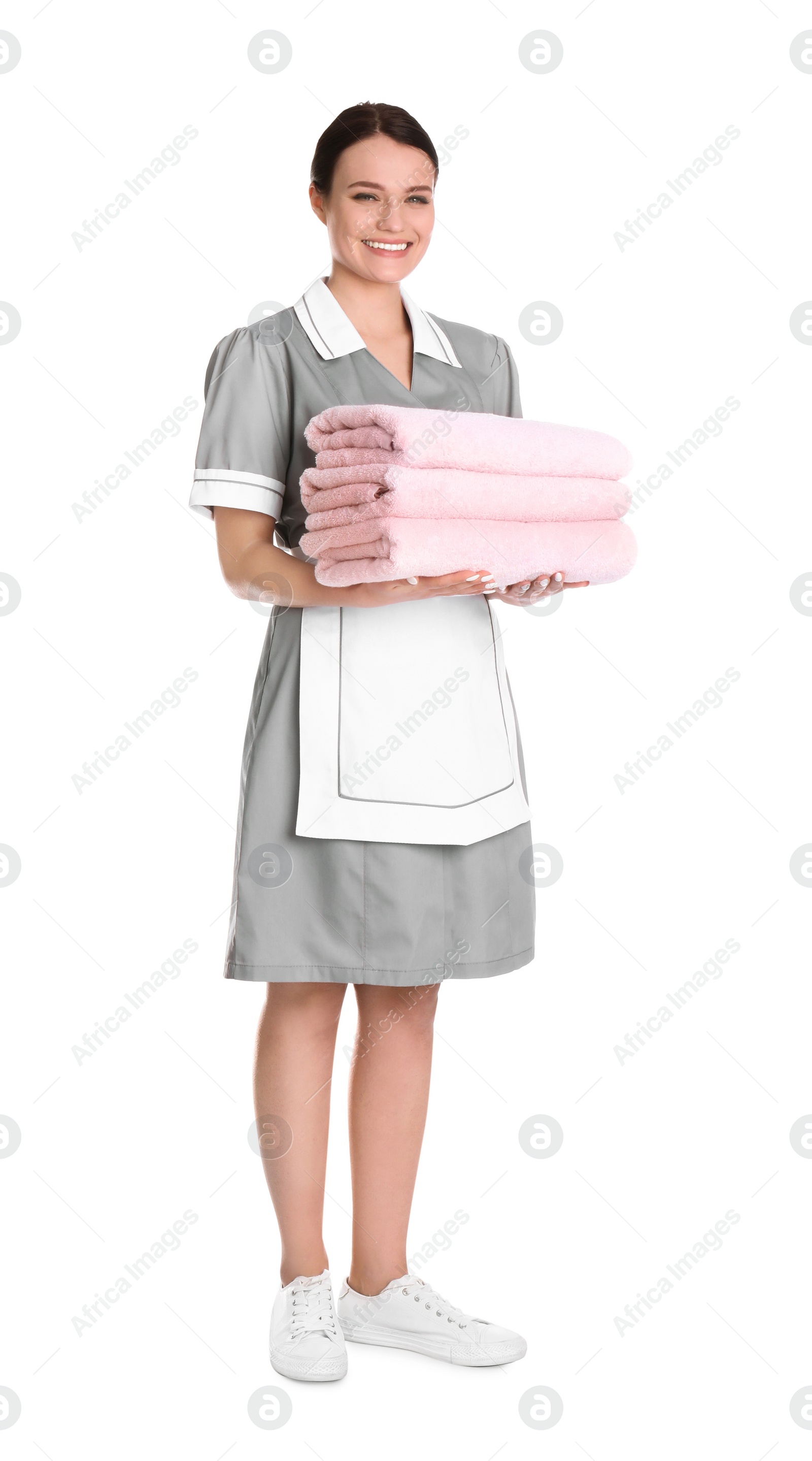 Photo of Young chambermaid holding stack of fresh towels on white background