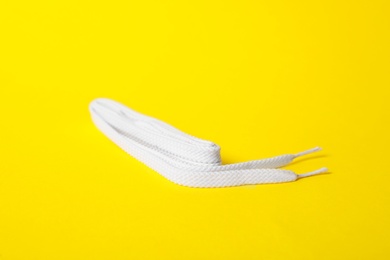 Photo of White shoe lace on yellow background. Stylish accessory