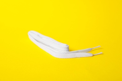 White shoe lace on yellow background. Stylish accessory