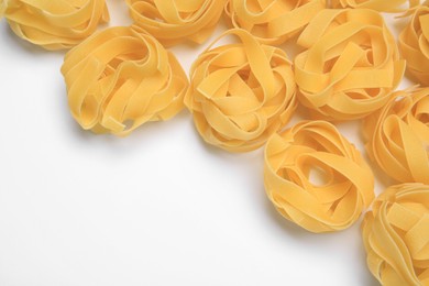 Photo of Raw tagliatelle pasta on white background, top view. Space for text