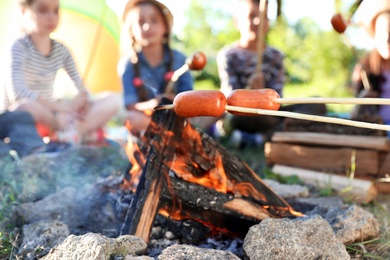 Photo of Frying sausages on bonfire, closeup. Summer camp