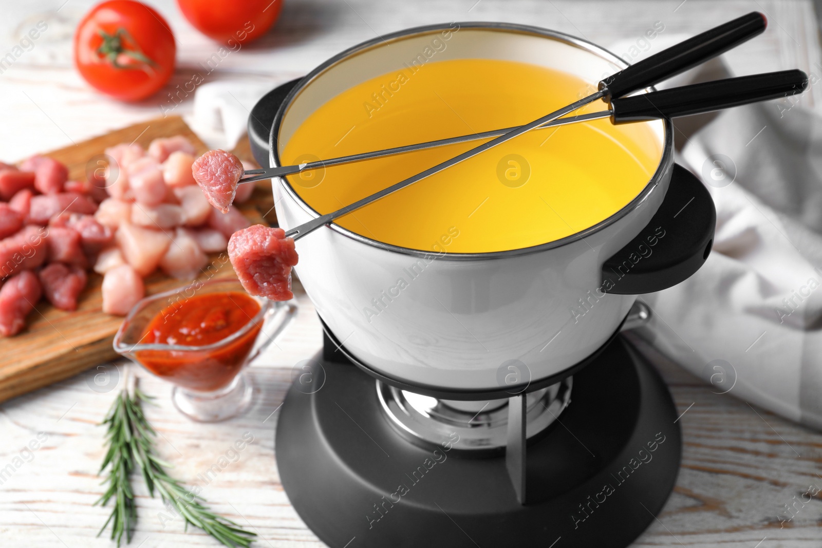 Photo of Fondue pot and forks with raw meat on table