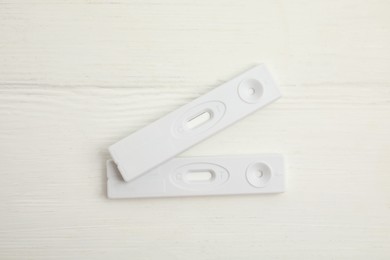 Photo of Two disposable express tests for hepatitis on white wooden table, flat lay