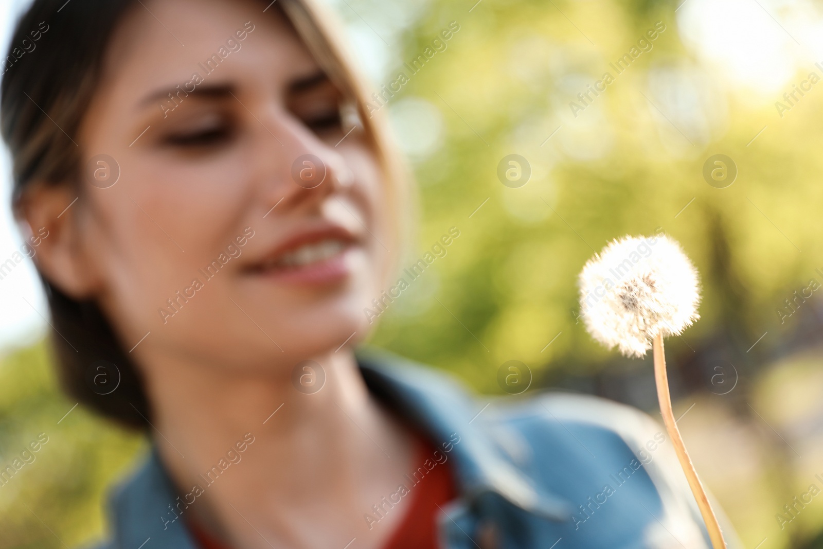 Photo of Young woman with dandelion in park on sunny day, closeup. Allergy free concept