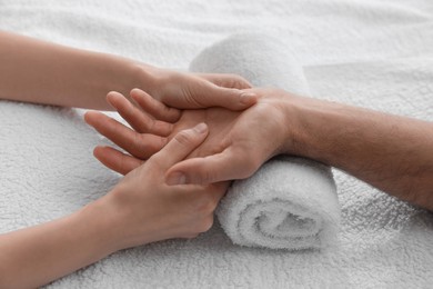 Photo of Man receiving hand massage on soft towel, closeup