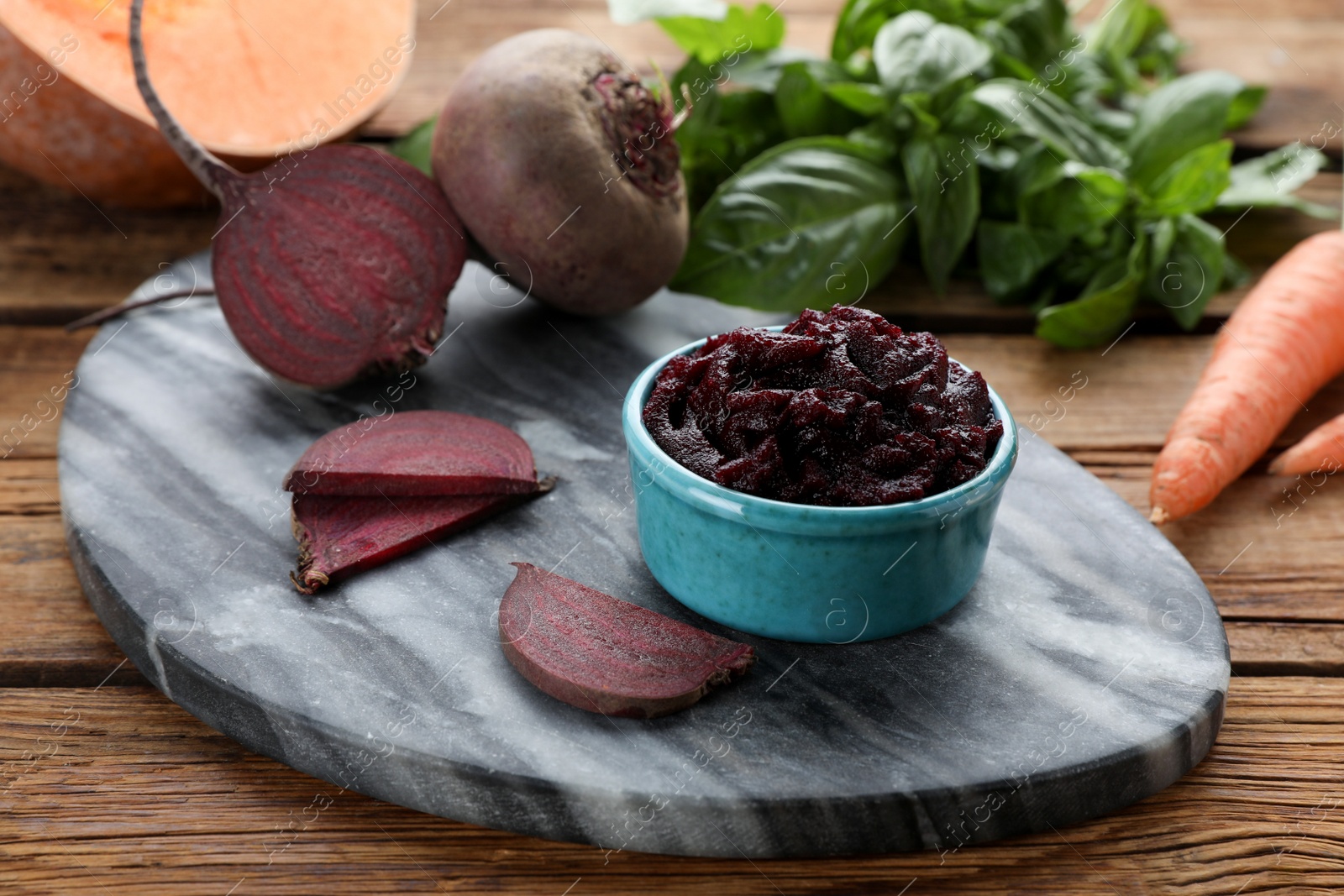 Photo of Bowl with tasty beet puree and ingredients on wooden table