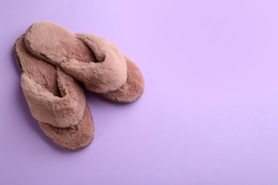 Pair of stylish soft slippers on violet background, flat lay. Space for text